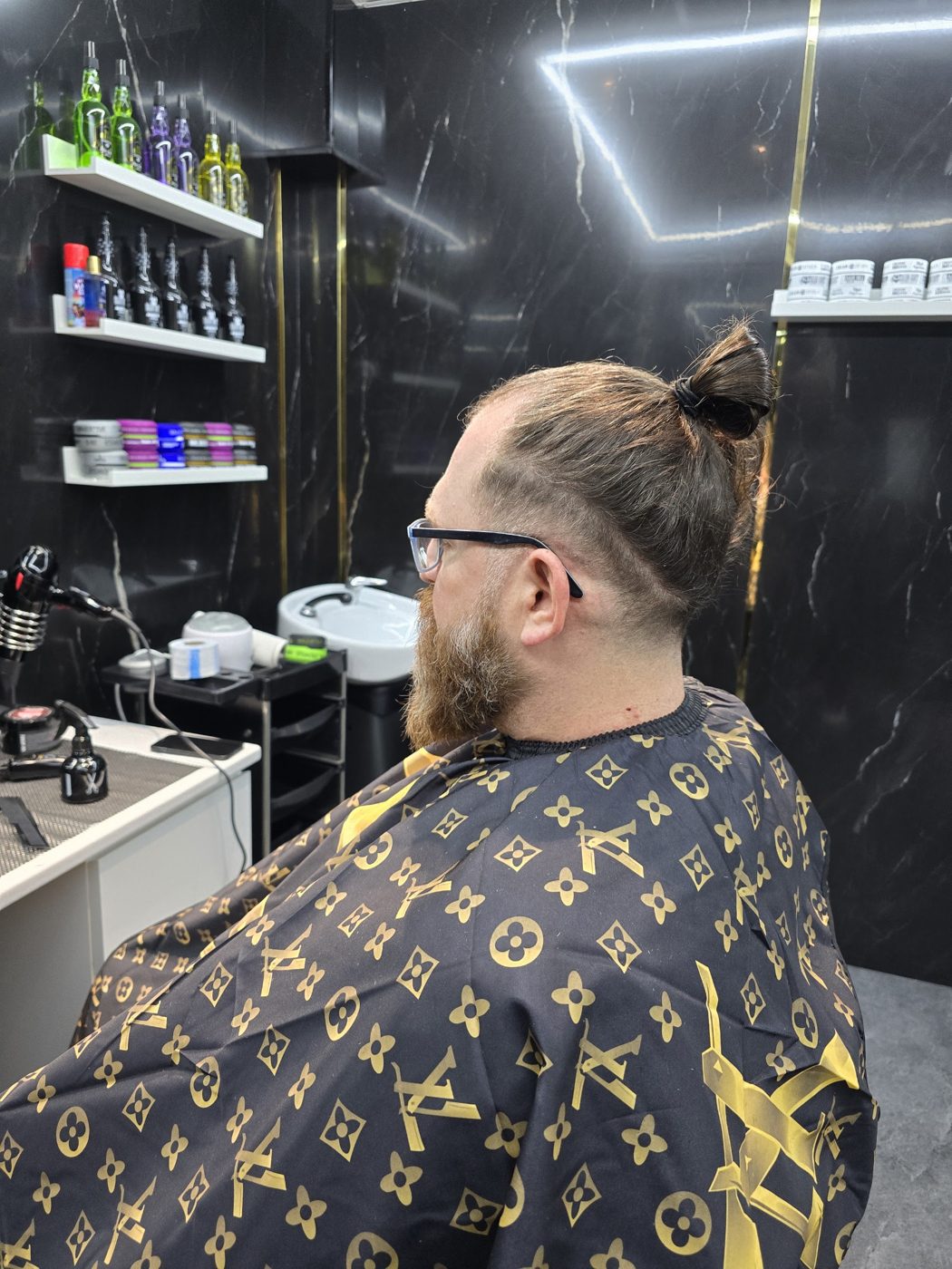 Klant met lang haar in een knot en volle baard, in de stoel bij Fadi